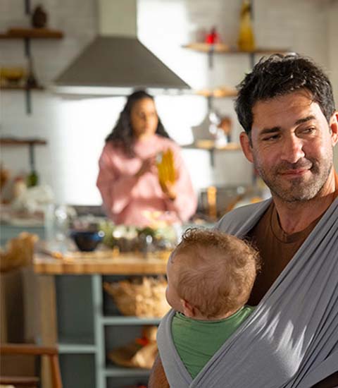 Vater mit Baby im Arm steht in der Küche
